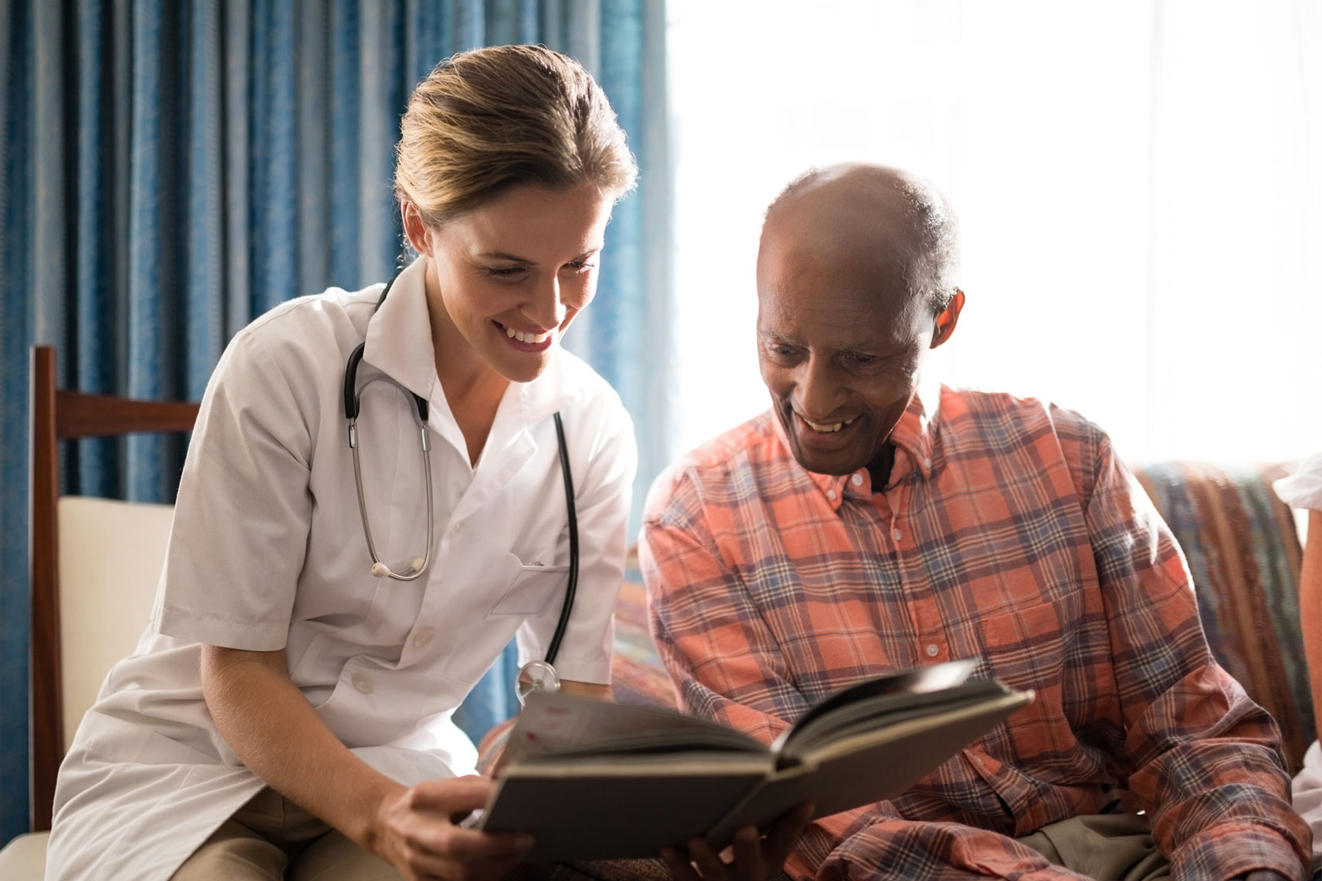 Smiling female doctor reading book with senior man sitting on